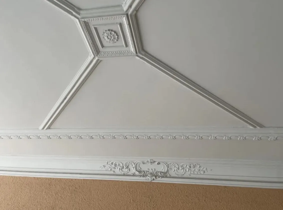 Deckenrosette und Stuckleisten in einem Altbau, frisch gestrichen.