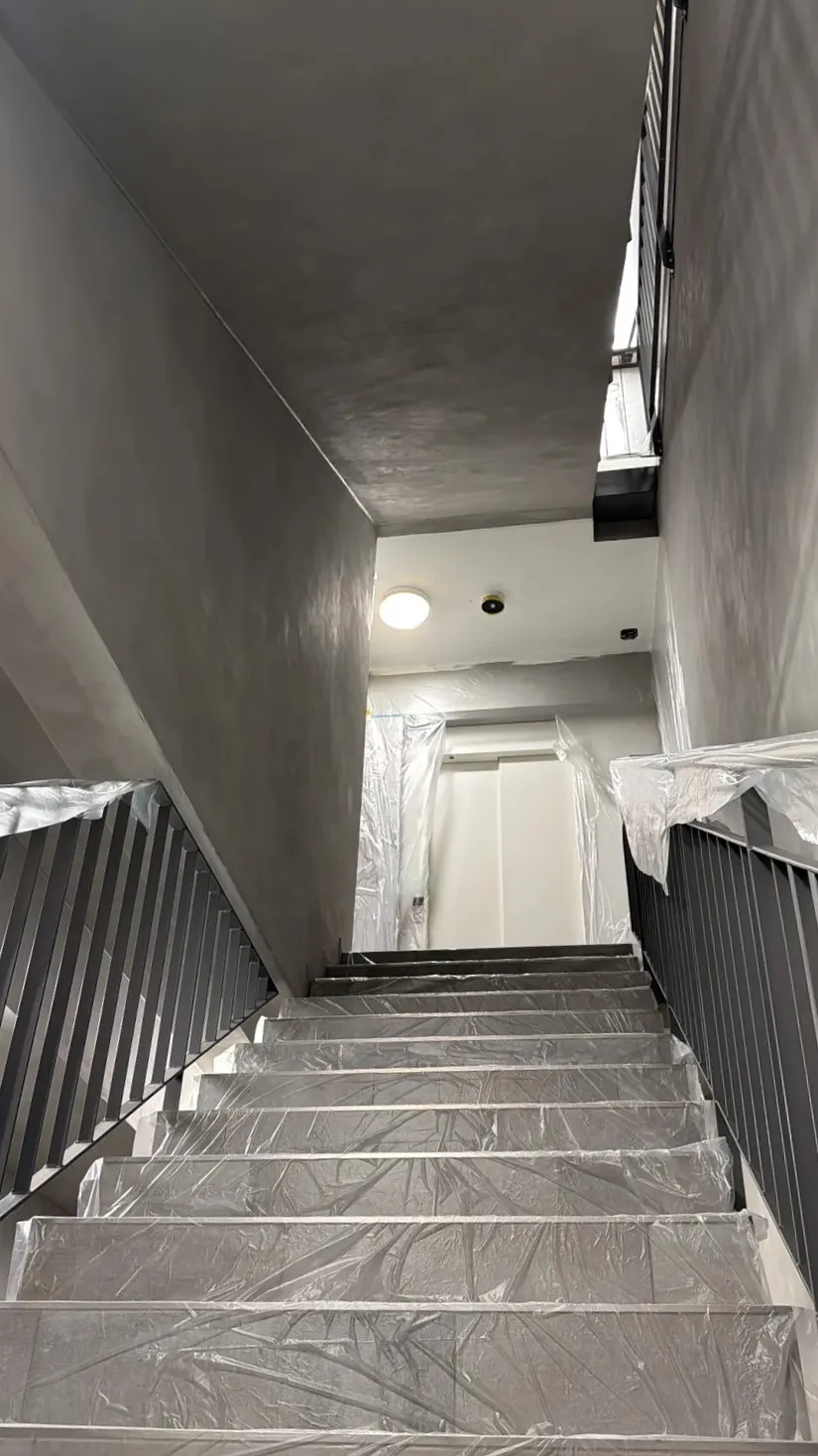 Treppenhaus während der Arbeiten: Geländer, Stufen und angrenzende Flächen sind mit Folie abgedeckt und abgeklebt.